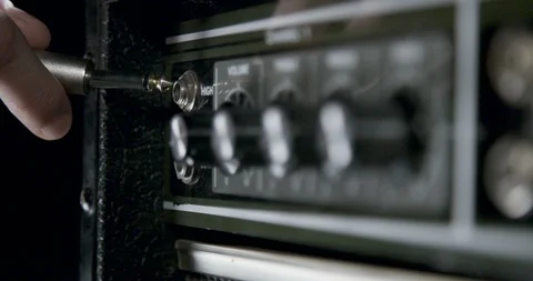 Hand plugs in jack cable into a guitar amplifier and turn amp knobs Stock Footage