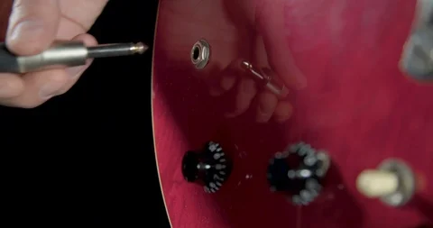 Hand plugs in jack cable into a guitar and turn on volume buttons Video stock 102047734