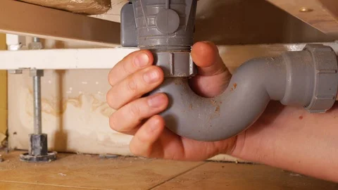 Hand of a plumber man. Locksmith repairs drain under the bath, eliminates clo Stock Footage 128960272