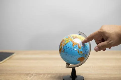 Hand point on the world model stand on brown table with white background copy Stock Photos