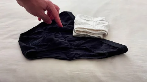 Hand Pointing at Black and White Underwear on Soft White Surface 스톡 동영상 326095484