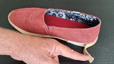 Hand pointing at detached jute sole of damaged canvas espadrille shoe Stock Footage 341312753