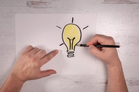 Hand pointing at doodle of bright idea lightbulb other hand holding pencil Stock Photos