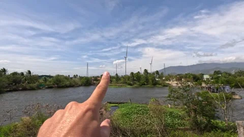 A hand is pointing with a finger at windmill electric turbines Phan Rang Vietnam Stock-Footage 242133716