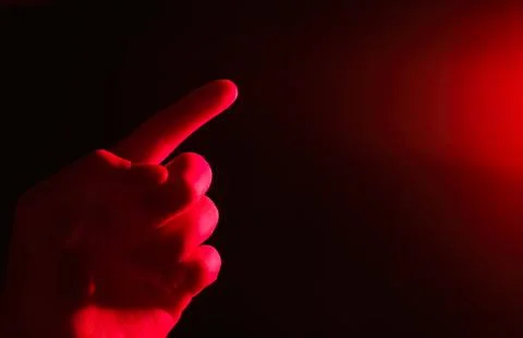 Hand pointing at red light in dark background 写真素材