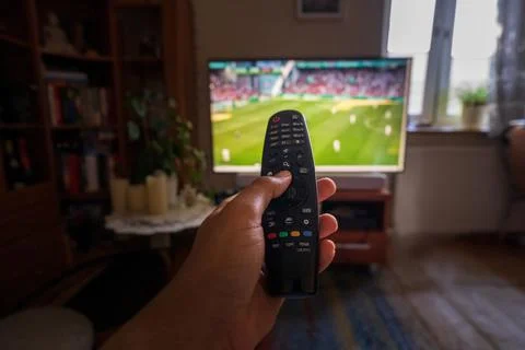 A hand pointing remote control at tv or television set with soccer or footbal Stock Photos