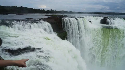 A hand pointing toward the powerful Devils Throat waterfall at Iguazu in slow Stock Footage 345027389