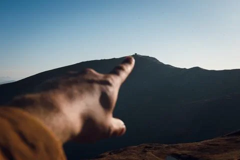 Hand Pointing Towards Distant Mountain Peak Stock Photos