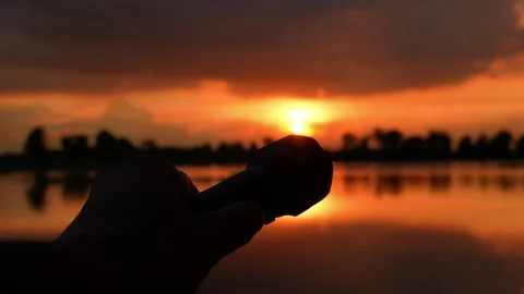 A hand points a flashlight at the sunset. Video stock 316141889