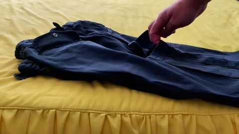 Hand Points to Folded Pants on Yellow Ruffled Bedspread 스톡 동영상 322090026
