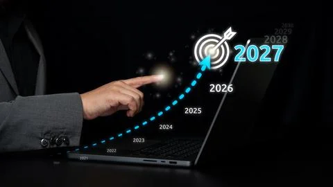 Hand points at a glowing 2027 target icon above laptop, combining business .. Stock Photos