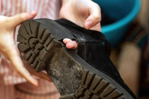 Hand points through a hole in a worn-out shoe, highlighting the damage. The i Stock Photos