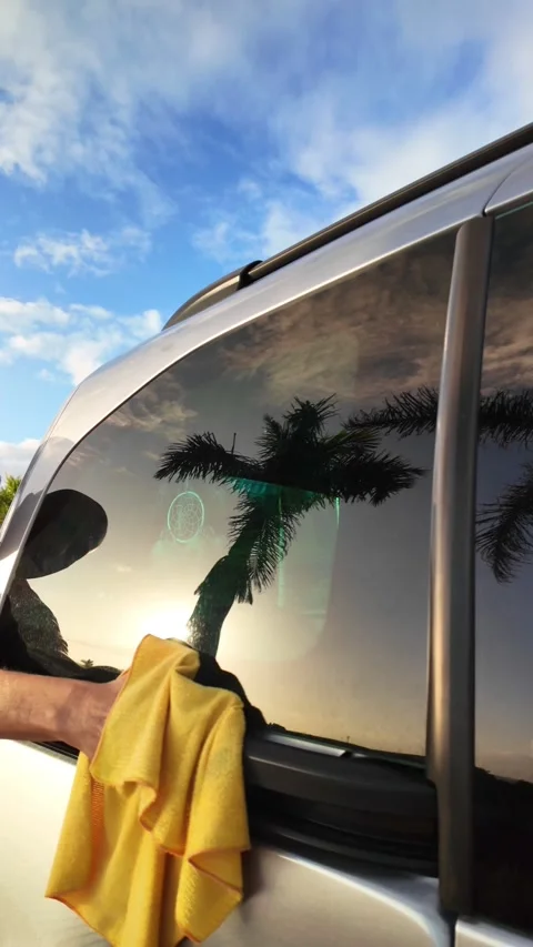 Hand polishing a silver car window at sunset Vídeos de archivo 330554664