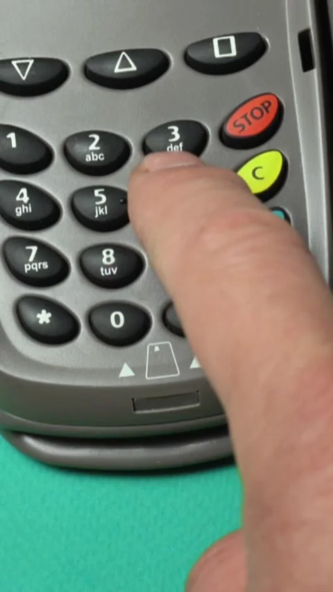 A hand positioned above the keypad of a payment terminal presses the PIN numbers Stock Footage 339366864