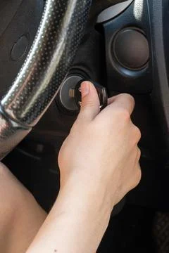 Hand positioned to insert a key into the ignition of a car, with the steering Stock Photos