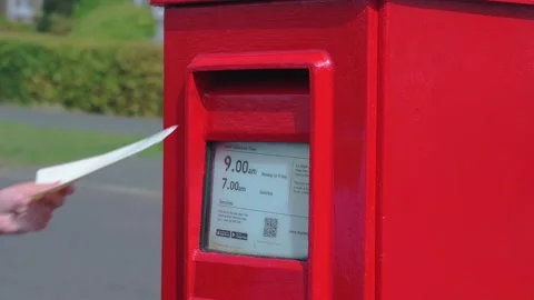 Hand posting letter in a red Royal Mail rectangular postbox in England, UK Stockbeeldmateriaal 205730511