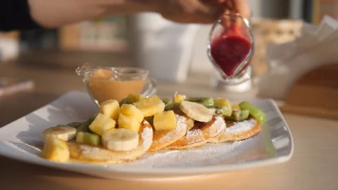Hand Pouring Berry Sauce On Vegan Pancakes With Fruits For Breakfast. Video stock 123788668