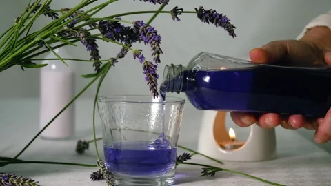 Hand pouring bubble bath with fresh lavender flowers for aromatherapy Stock Footage 314258329