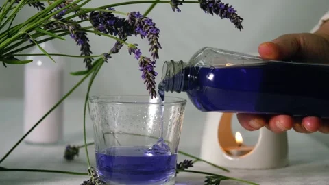 Hand pouring bubble bath with fresh lavender flowers for aromatherapy Stock Footage 315057874