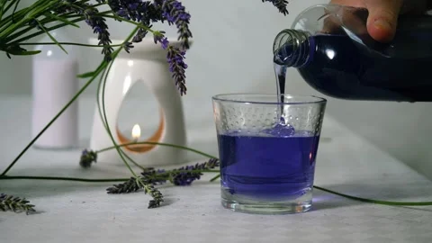 Hand pouring bubble bath with fresh lavender flowers for aromatherapy Stock Footage 318907301