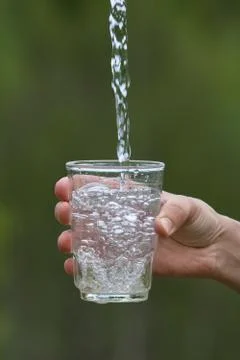 Hand pouring clean natural water into a glass Stock Photos