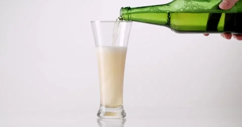Hand pouring cold fresh beer into a glass from a green bottle Stock Footage 329293256
