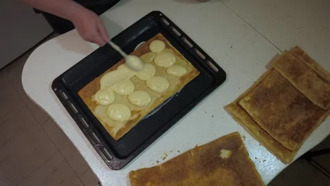 Hand pouring cream over rectangular pastry pieces Vidéo 342361759