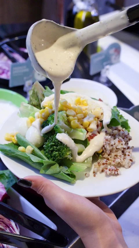 Hand Pouring Creamy Dressing Over Fresh Salad Buffet Plate Vídeo Stock 323680640