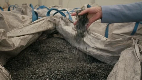 Hand Pouring Dark Plastic Granulate into Big Bag, Recycling Facility, Close Up Stock Footage 341298231