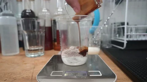 Hand pouring espresso over ice balls in disposable transparent plastic glass Stock Footage 236451880