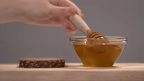 Hand Pouring Honey on a Multigrain Bread Slice Stock Footage 110847705