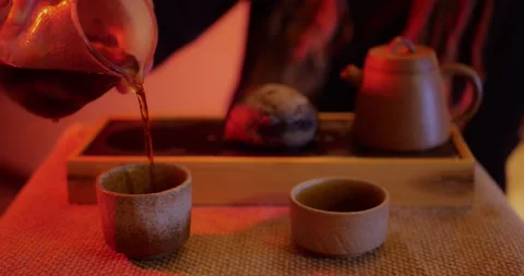 Hand pouring hot tea into ceramic cups with a teapot visible in warm... Vidéo 319883488