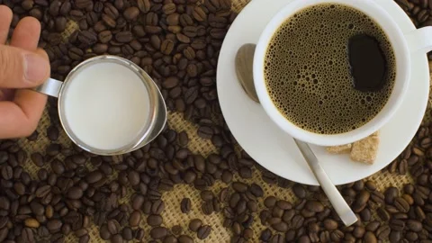 Hand pouring milk into coffee Stock Footage 137030435