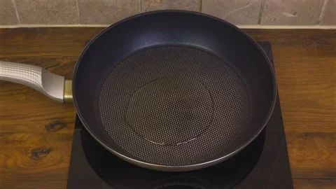 Hand pouring oil then adding sliced onions to frying pan Vídeos de archivo 345422137
