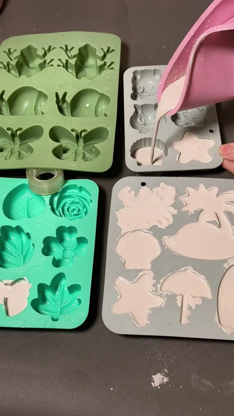 Hand pouring plaster solution into silicone molds with intricate designs, Stock Footage 337538351