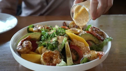 Hand pouring salad dressing on summer tropical mango shrimp avocado salad Stock-Footage 88840641