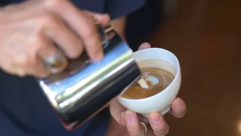 Hand pouring steamed milk for making latte coffee Stock Footage 121132263