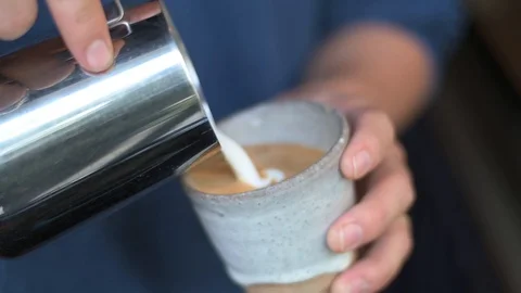 Hand pouring steamed milk for making latte coffee Video stock 121133374