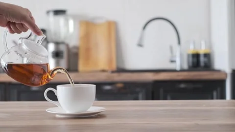 Hand pouring tea from glass tea pot to the cup Stock-Footage 247358420