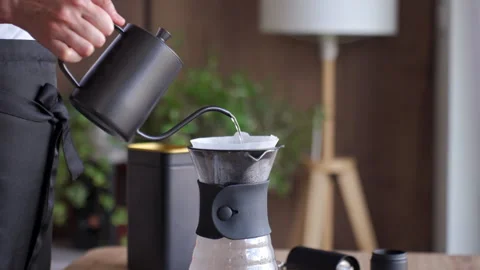 Hand pouring water into pour over coffee dripper during drip coffee brewing Stock Footage 336940754