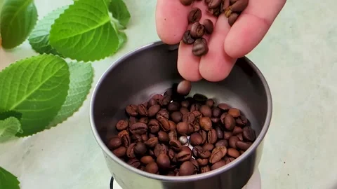 A hand pours coffee beans into a coffee grinder Stock Footage 307666971