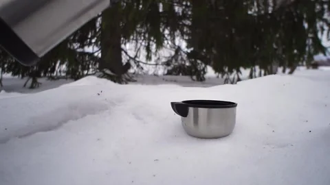The hand pours hot tea from the thermos into a mug in winter in the park. Stock Footage 132965462