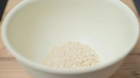 A hand pours rice into a large white bowl for cooking Stock-Footage 338298392