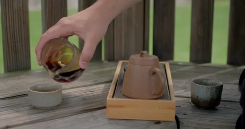 Hand pours tea into a ceramic cup outdoors during a traditional tea... Stock Footage 316915679