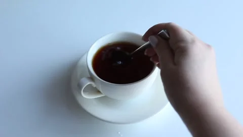 The hand pours a teaspoon of sugar into the tea and stirs. Stock Footage 168935164
