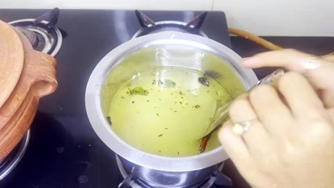 Hand pours warm liquid into rice vessel in indian kitchen Stock Footage 310288408