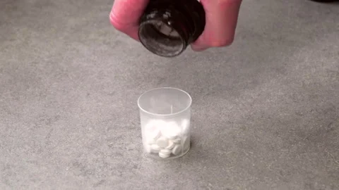 Hand pours white pills into clear cup Stock Footage 341766515