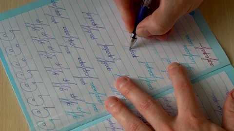 Hand is practicing handwriting in calligraphy notebook in slow motion Stock Footage 149963200