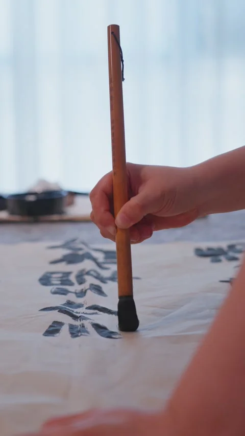 Hand practicing traditional calligraphy indoors with long brush Stock Footage 340960340