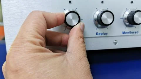 A Hand Precisely Adjusts a Knob on a White Control Panel Highlighting Atten.. Stock Photos
